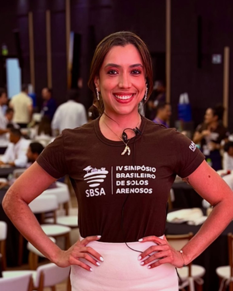 Carla Letícia sorrindo, de mãos na cintura, em um simpósio sobre solos arenosos